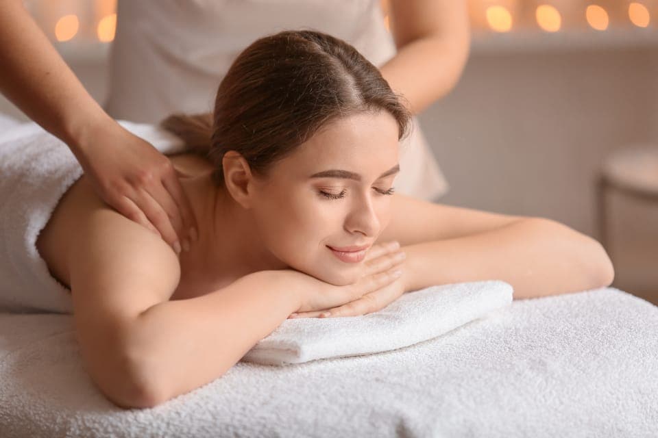 Kỹ thuật viên massage lưng cho khách đang nhắm mắt thư giãn