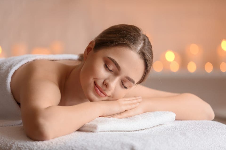 Khách nằm sấp nhắm mắt thư giãn trên giường spa