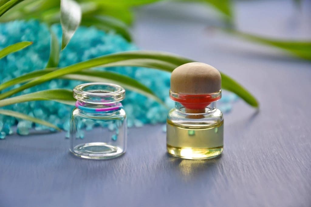 Lọ thuỷ tinh rỗng và lọ dầu nút gỗ bên muối tắm xanh