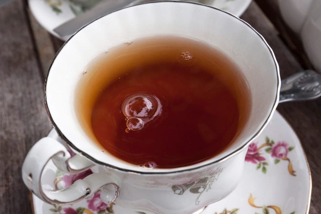 Tách trà nóng trên đĩa sứ hoạ tiết hoa