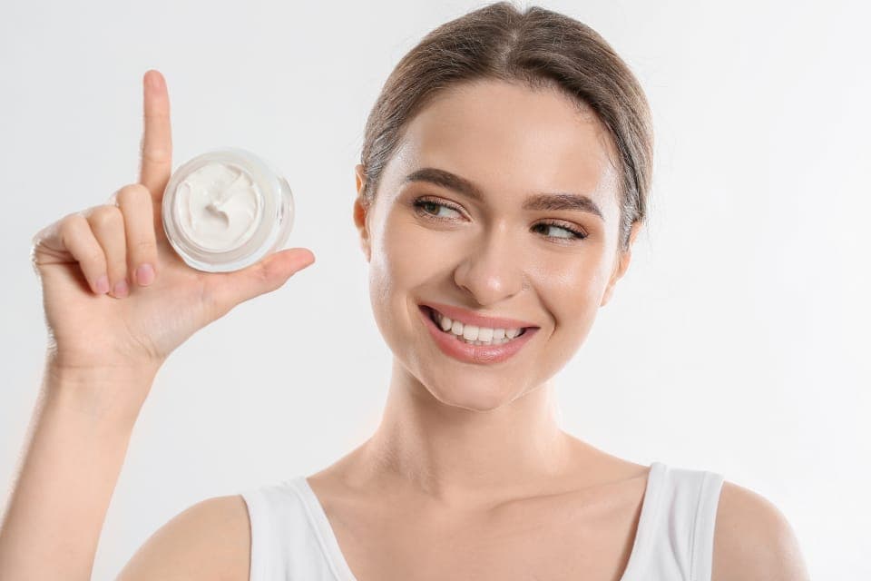 Người phụ nữ cầm hũ kem dưỡng đã mở nắp