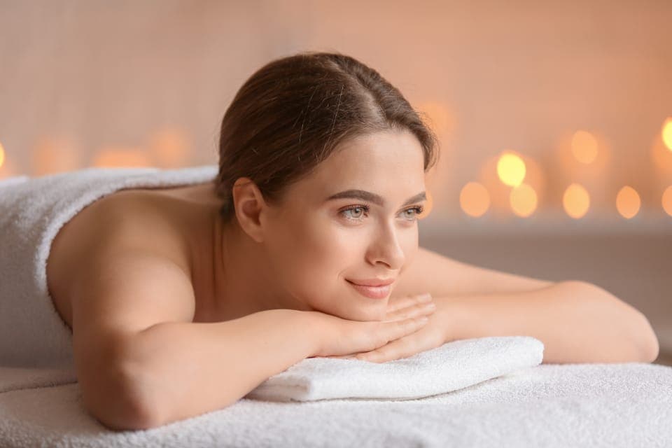Khách nằm sấp mỉm cười, nền đèn nến mờ