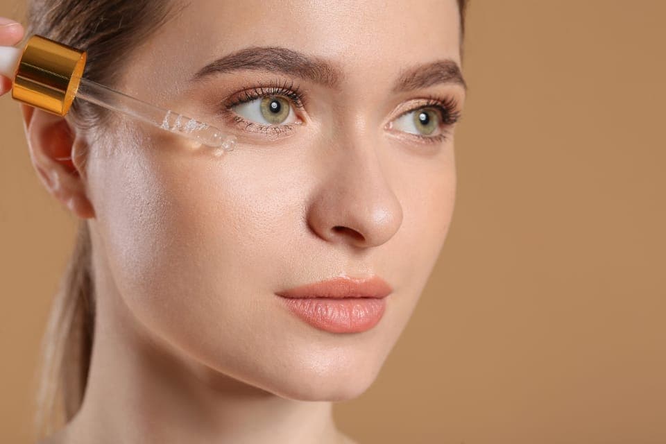 Người phụ nữ nhỏ serum lên da mặt bằng ống nhỏ giọt