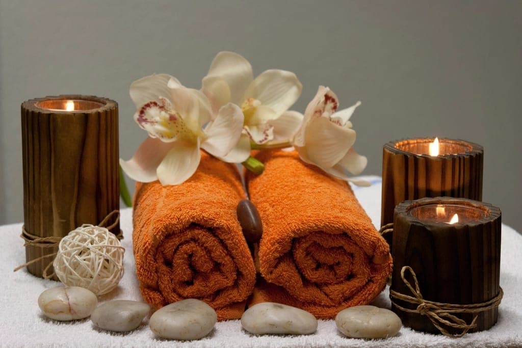 Khăn cam cuộn, hoa lan và nến trong ống gỗ