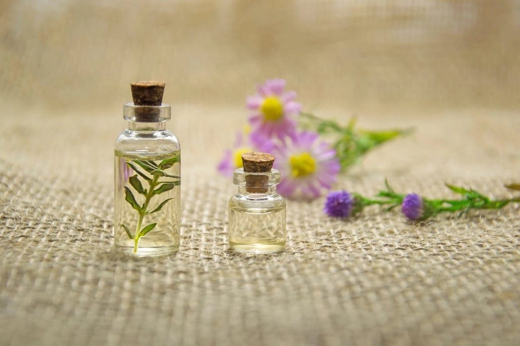 Hai lọ tinh dầu nút bần và hoa cúc tím trên vải bố