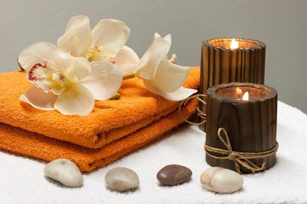 Khăn cam, hoa lan trắng, nến gỗ và đá cuội