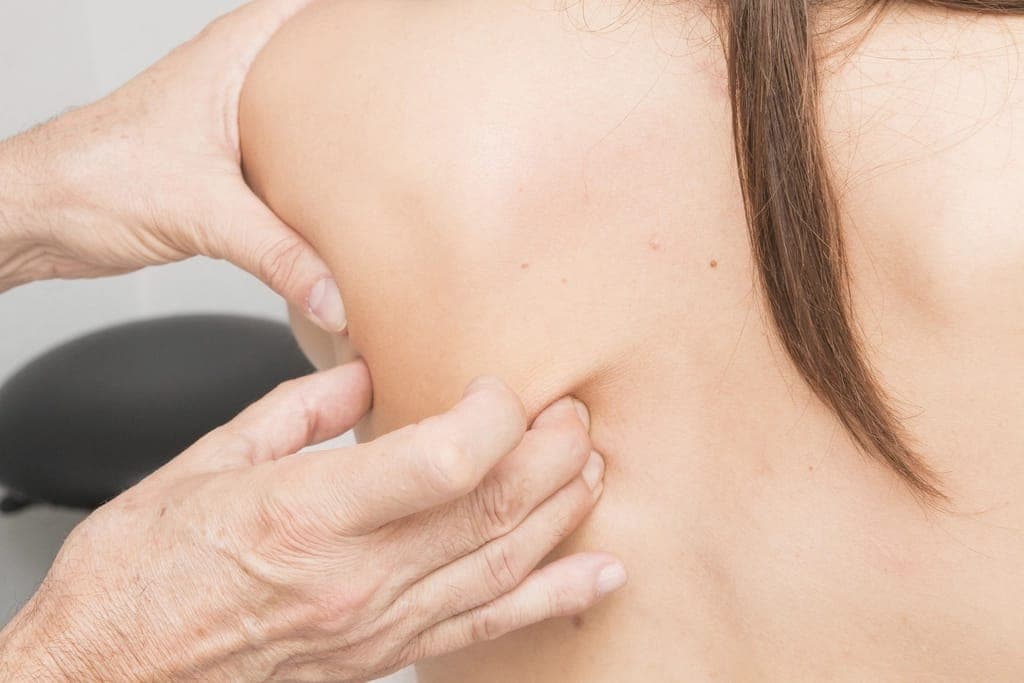 Hai bàn tay ấn vào vùng bả vai của một người tóc dài