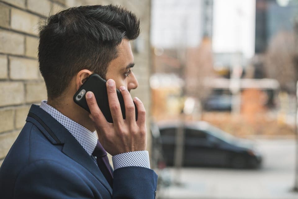 Người đàn ông mặc vest nghe điện thoại ngoài phố