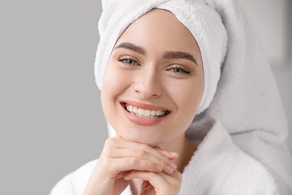 Người phụ nữ quấn khăn tóc, mặc áo choàng tắm, mỉm cười