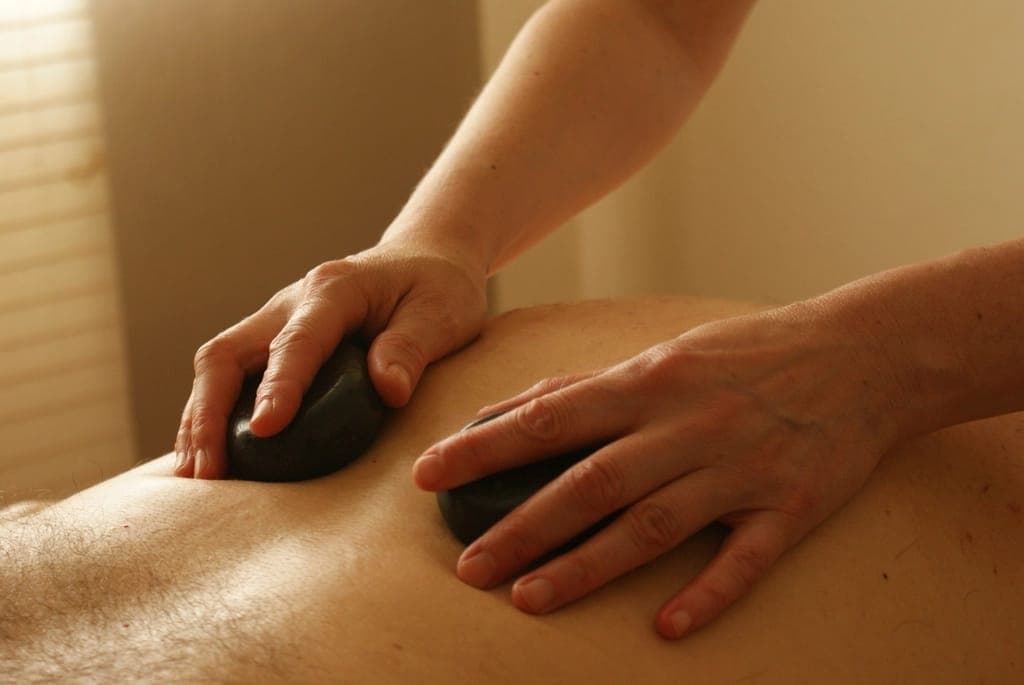 Kỹ thuật viên đặt đá nóng lên lưng khách