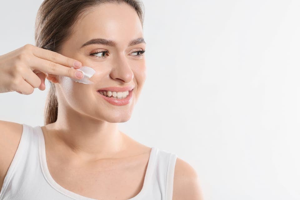 Người phụ nữ thoa kem lên má bằng đầu ngón tay