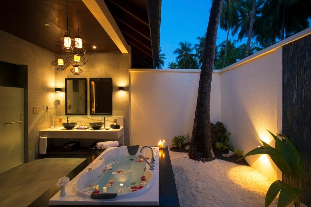 Phòng tắm spa ngoài trời có bồn rải hoa và đèn nến buổi tối
