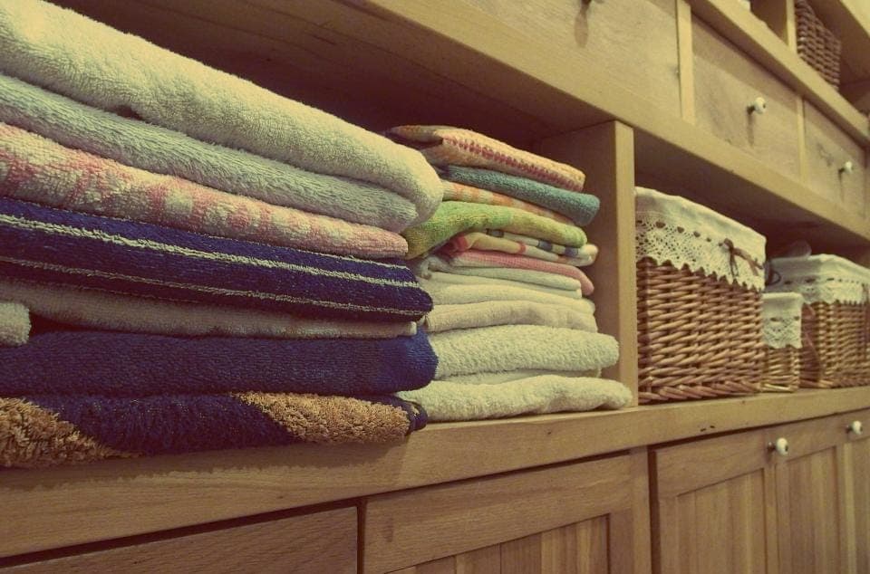 Khăn gấp xếp trên kệ gỗ cạnh giỏ mây