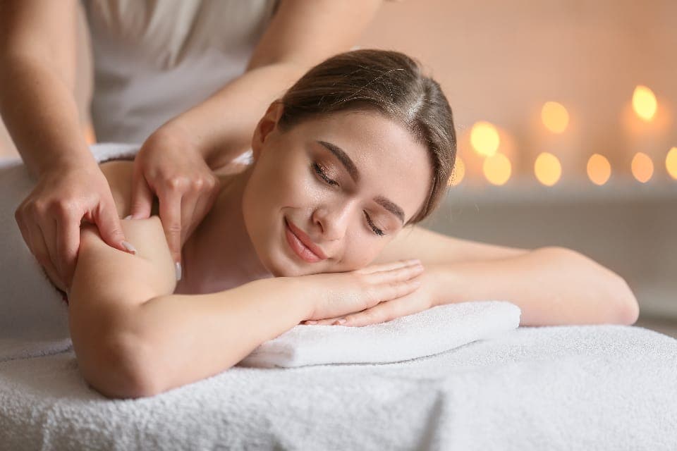 Kỹ thuật viên massage vai cho khách nằm sấp trên khăn trắng