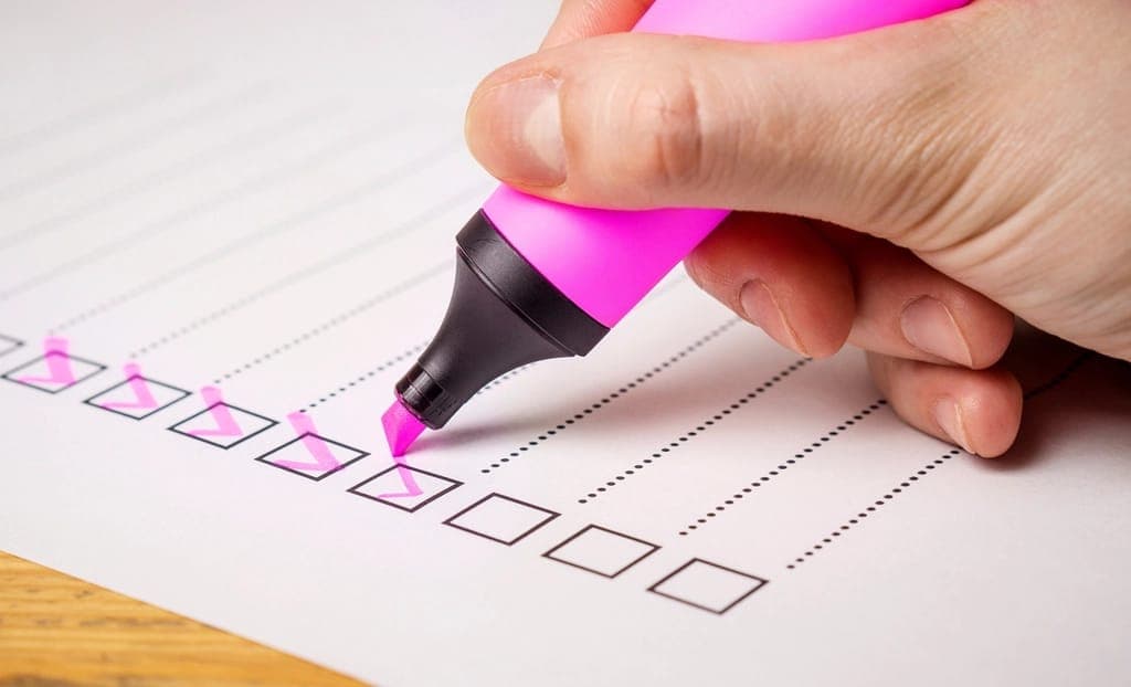 Tay cầm bút dạ hồng đánh dấu vào các ô vuông trên tờ phiếu
