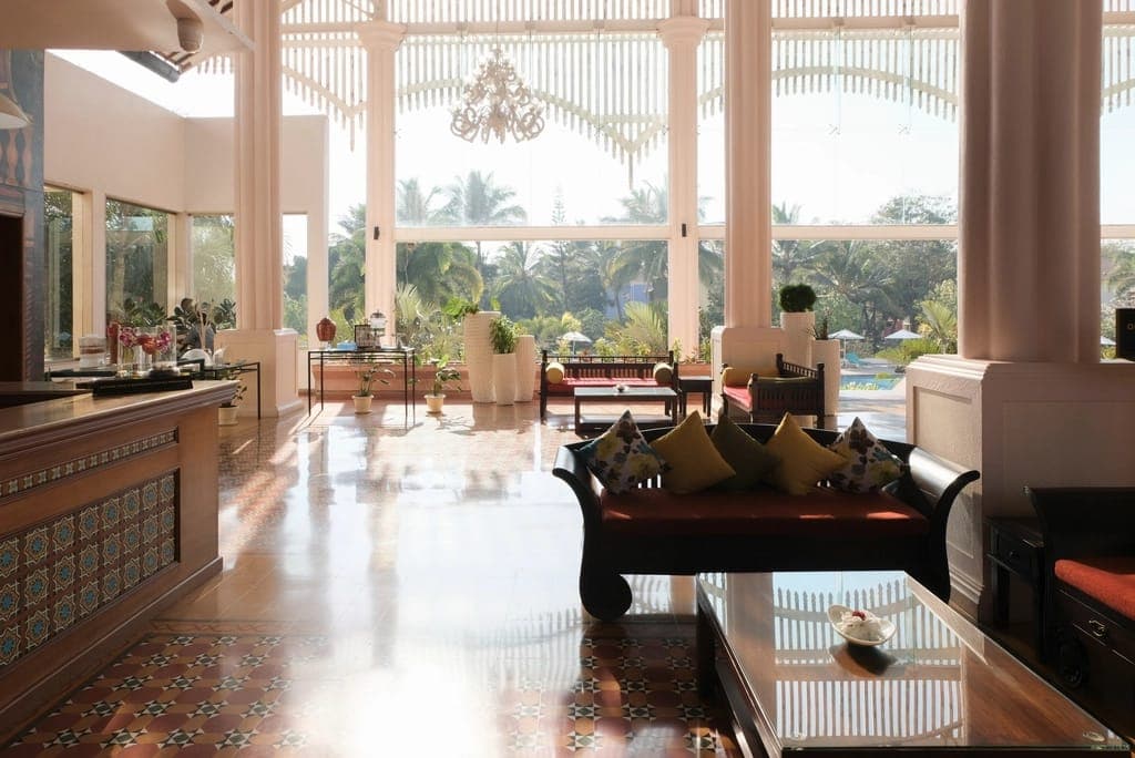 Sảnh rộng lát gạch bóng, có sofa và cửa kính lớn nhìn ra vườn cây