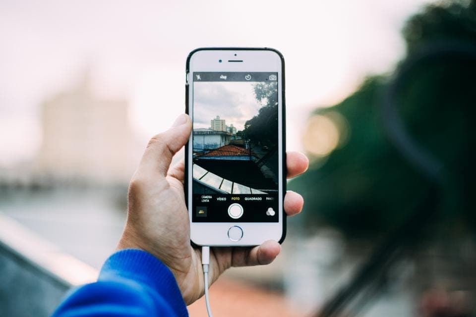 Bàn tay cầm điện thoại đang mở camera hướng ra đường phố