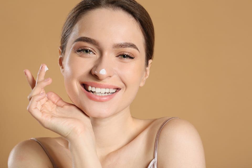 Người phụ nữ chấm kem lên mũi, mỉm cười