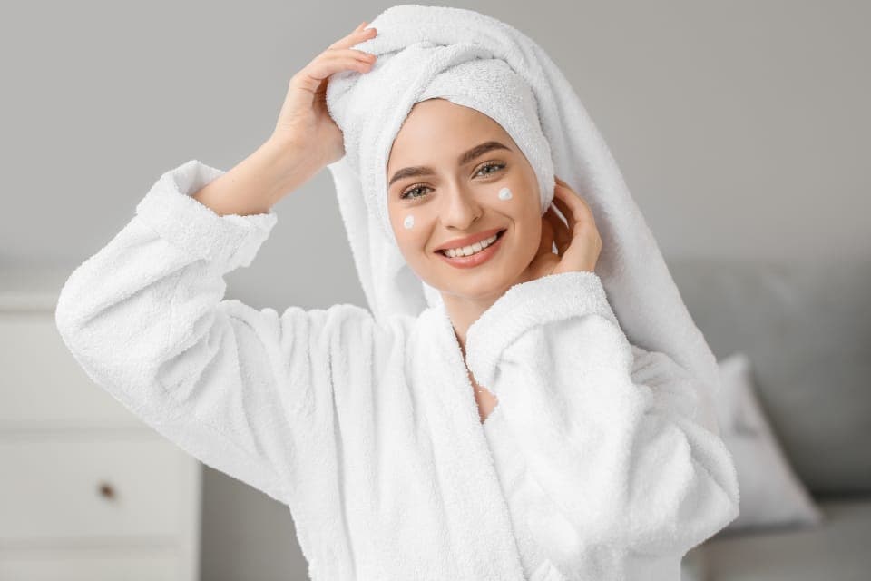 Người phụ nữ mặc áo choàng, quấn khăn tóc sau khi gội