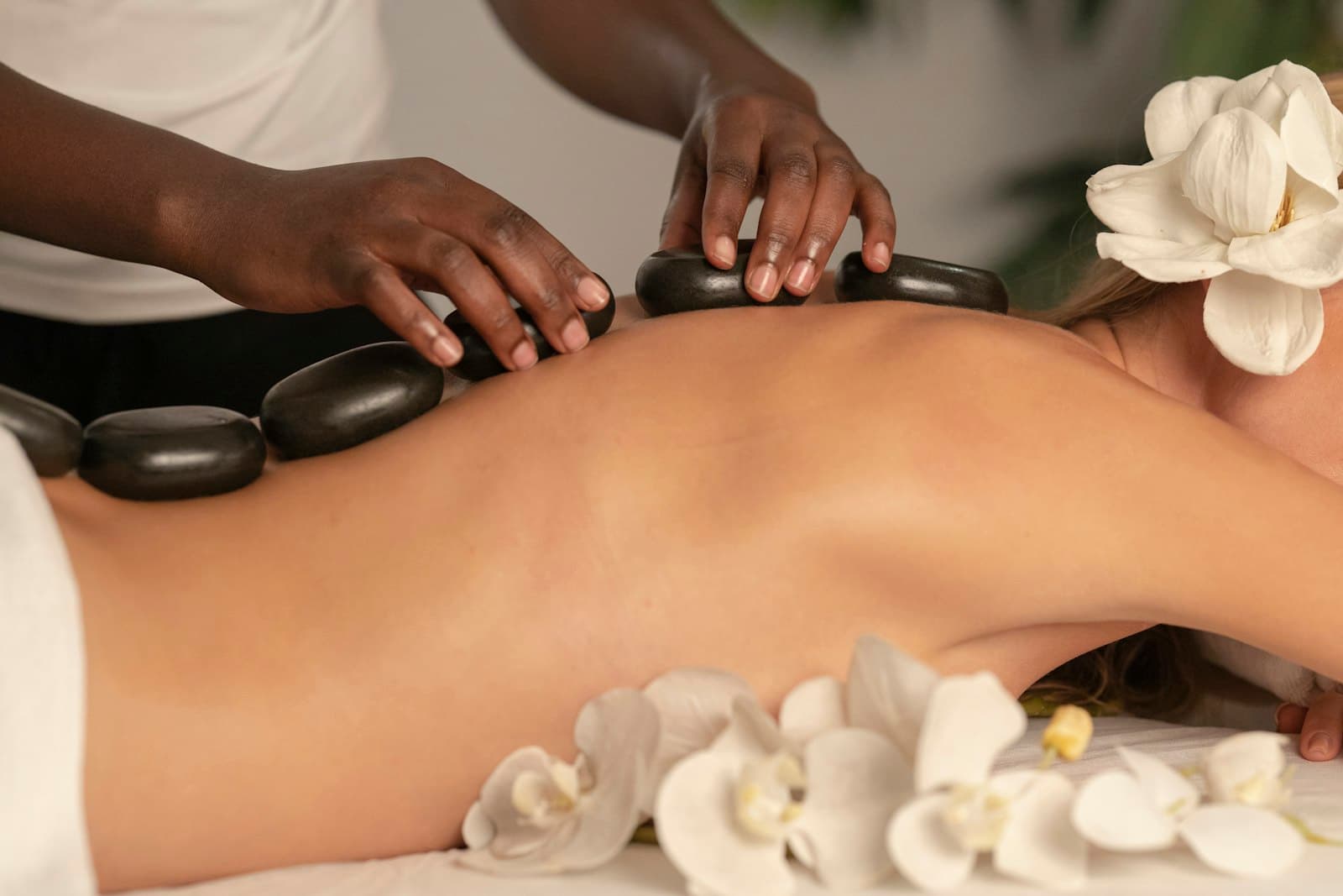 Đá nóng và hoa trắng xếp trên lưng khách trong buổi massage