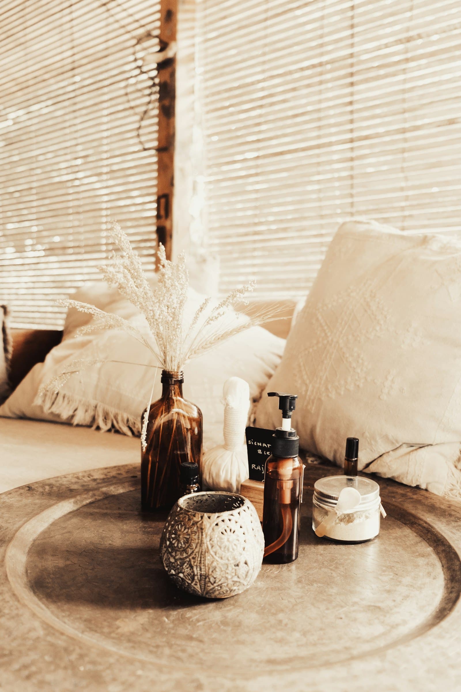 Giường spa với gối màu kem và hoa khô, không gian nhẹ nhàng cho người mới